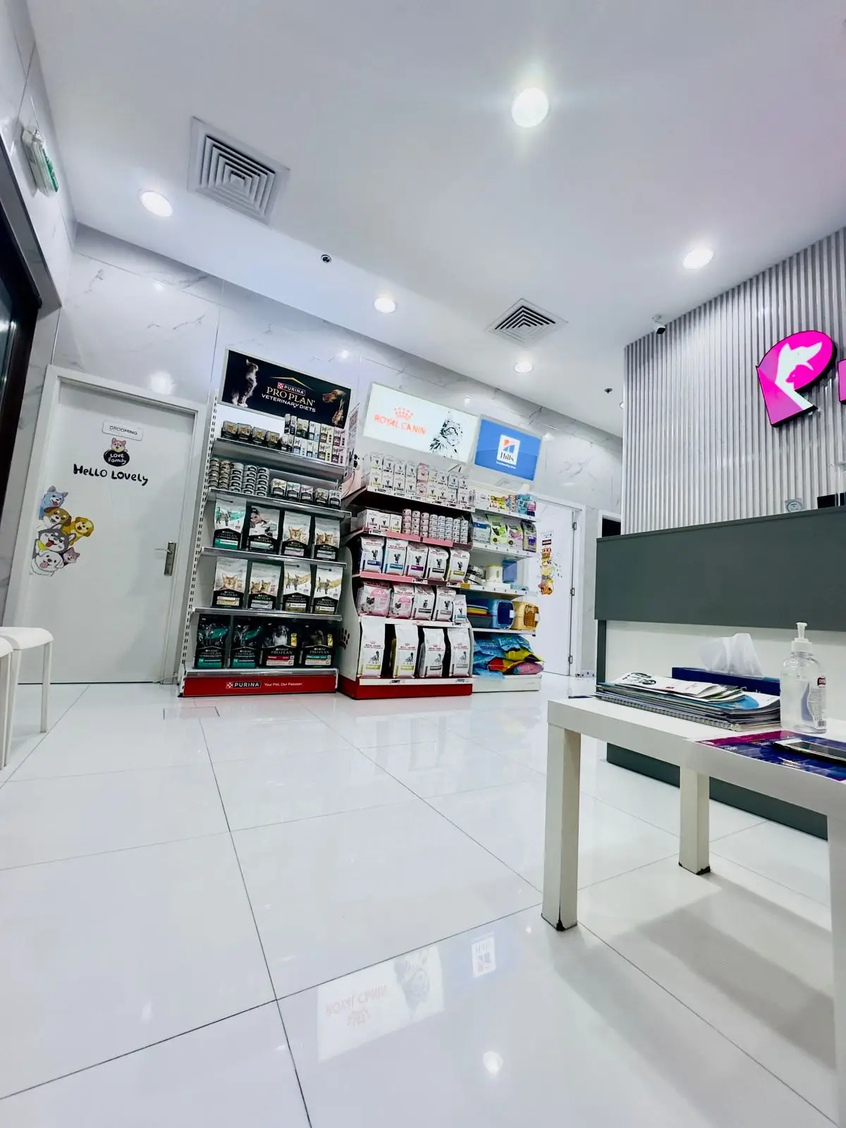 The Petflix lobby with pet food shelves, a waiting bench and the pink sign above the reception desk